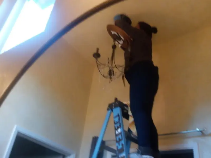 Electrician installing a chandelier in a Wales residence